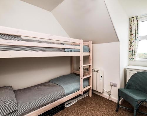 a bedroom with two bunk beds and a chair at Pinewood 14 in Polzeath