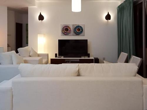 uma sala de estar com um sofá branco e uma televisão de ecrã plano em Great Location Living, Modern 2-Bed Apartment with Pool & Gym Access, All Amenities em Sri Jayewardenepura Kotte