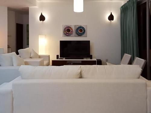 a living room with a white couch and a flat screen tv at Great Location Living, Modern 2-Bed Apartment with Pool & Gym Access, All Amenities in Sri Jayewardenepura Kotte