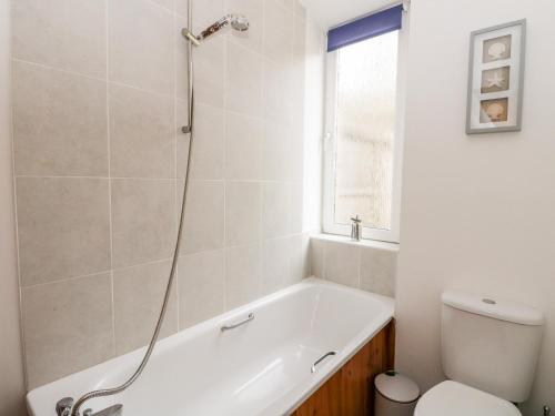 a bathroom with a bath tub and a toilet at 1 Station Cottages in Trinafour