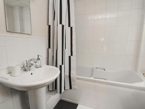 a white bathroom with a sink and a bath tub at Cwmberwyn in Cardigan