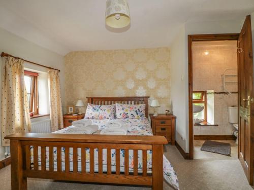 Un dormitorio con una gran cama de madera con almohadas en Poppy Cottage, en Penrith