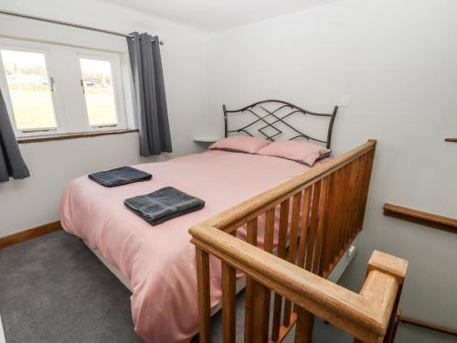 um quarto com uma cama com lençóis cor-de-rosa e almofadas cor-de-rosa em The Annexe em Keighley