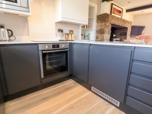 a kitchen with blue cabinets and an oven at Moss Side Retreat in Skipton