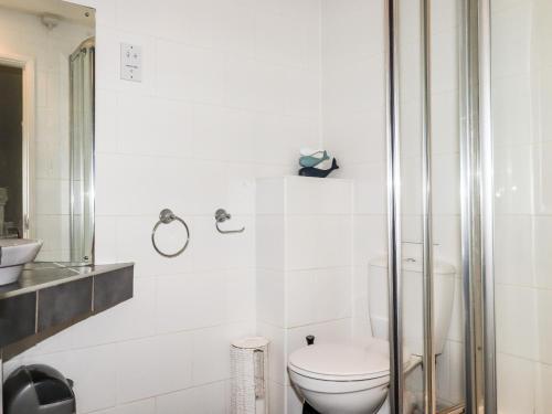 a white bathroom with a toilet and a shower at 87 Atlantic Reach in Newquay