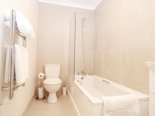 a white bathroom with a toilet and a bath tub at Apartment 2 in Southsea