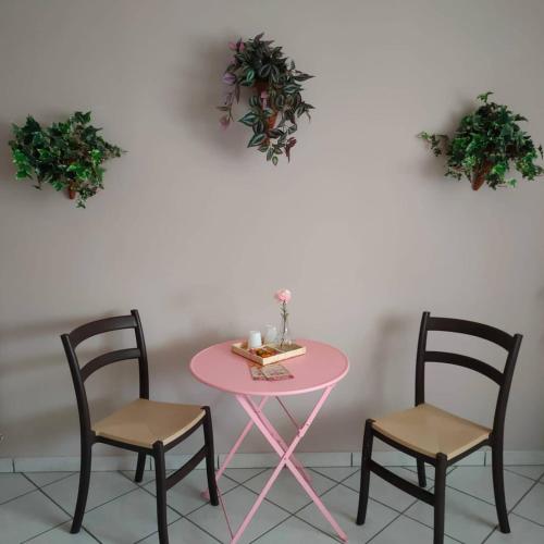 une table rose, deux chaises, une table et deux plantes dans l'établissement I capricci dell'etna 4 di Puglisi, à Mascalucia