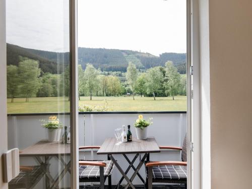 a balcony with a table and chairs and a large window at Ferienwohnung Kurparkblick Sauerland in Lennestadt