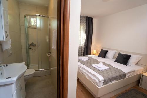 a bathroom with a bed and a shower and a sink at Olive & Almond Apartment in Bol