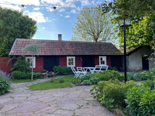 una casa roja con dos sillas blancas delante en Ölandsgården en Färjestaden