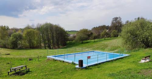 a large swimming pool in a field with two benches at Stodola in Cetenov