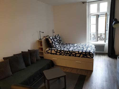 uma sala de estar com um sofá e uma cama em Au 16 em Dijon