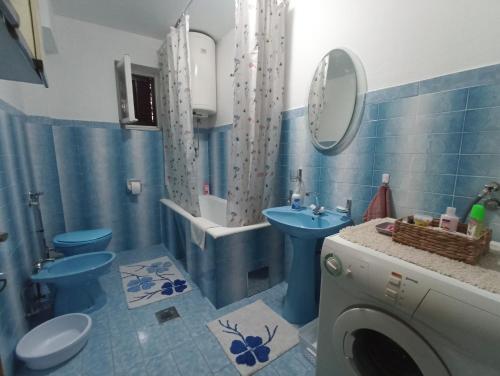 een blauwe badkamer met een wastafel en een wasmachine bij Apartman CITRUS Trebinje in Trebinje