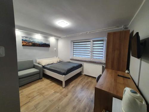 um pequeno quarto com uma cama e um sofá em Wczasy u Miry em Mielno