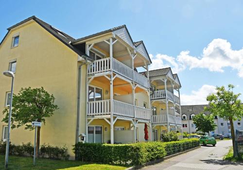 a yellow house with white balconies on a street at Ferienwohnung mit Balkon am Mönchgraben in Baabe