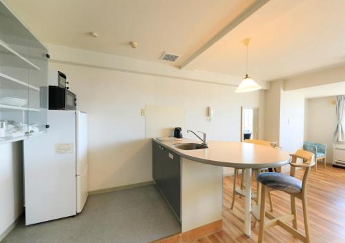 a kitchen with a sink and a table and a refrigerator at Katsuura Hilltop Hotel & Residence in Katsuura