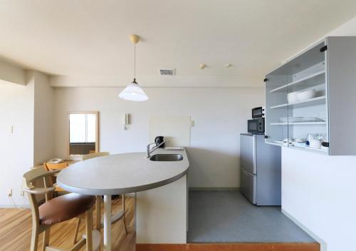 a kitchen with a table and a refrigerator at Katsuura Hilltop Hotel & Residence in Katsuura