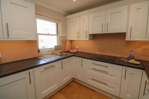 a kitchen with white cabinets and black counter tops at The Hideaway in Kingsbridge