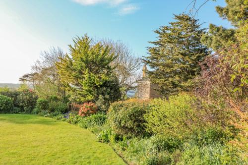 a garden with trees and a building in the background at The Hideaway in Kingsbridge