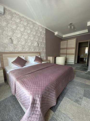 a bedroom with a large bed with a purple blanket at Hotel Dobrodiy in Vinnytsya