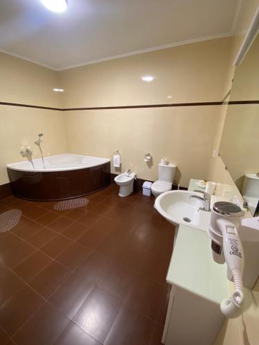 a bathroom with two toilets and a tub and a sink at Hotel Dobrodiy in Vinnytsya