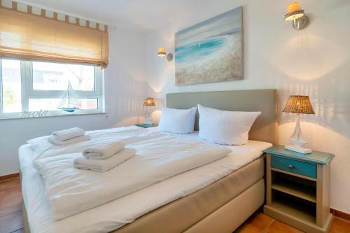 - une chambre avec un grand lit blanc et des serviettes dans l'établissement Residenz am Strand Wohnung 2-28, à Zingst