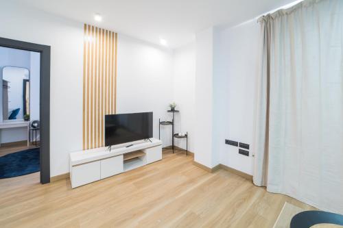 a living room with a flat screen tv on a white wall at BOUTIQUE APARTMENTS- LA GLORIA 1908 in Almería