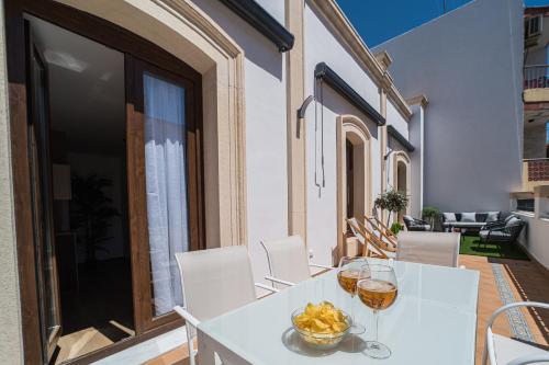 a table with wine glasses and a bowl of fruit on a balcony at BOUTIQUE APARTMENTS- LA GLORIA 1908 in Almería