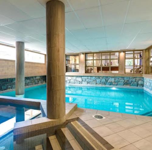 a large swimming pool with blue water in a building at Appartement 2 pièces Résidence les Fermes Emiguy Les Gets in Les Gets