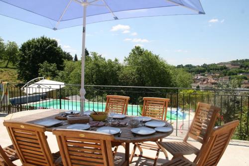 - une table en bois avec des chaises et un parasol sur la terrasse dans l'établissement Sarlat, 600 m à pied du centre historique, maison La Salamandre, à Sarlat-la-Canéda