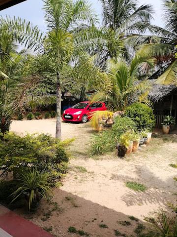 a red car parked in a yard with palm trees at Pleasant Park Holiday Inn in Trincomalee