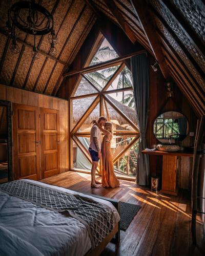 a man and a woman standing in a room with a window at Gili Treehouses Private Pool Hideaway in Gili Trawangan