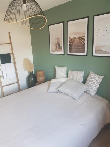 - une chambre dotée d'un lit blanc avec 4 photos sur le mur dans l'établissement Le Beausoleil, à Sète