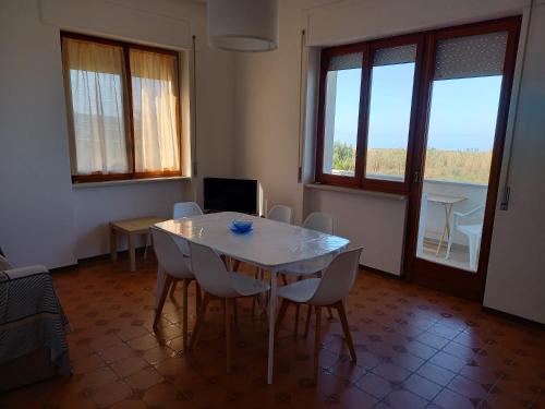 uma sala de jantar com mesa, cadeiras e janelas em Appartamento fronte mare costa dei trabocchi em Vasto
