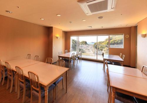 a dining room with tables and chairs and a large window at Katsuura Hilltop Hotel & Residence in Katsuura
