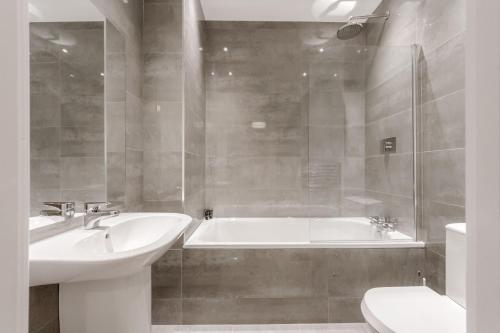 a bathroom with a sink and a tub and a toilet at Roomspace Serviced Apartments - Nouvelle House in Sutton