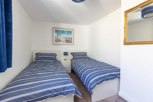 two beds in a room with blue and white stripes at Mabel Cottage in Torquay