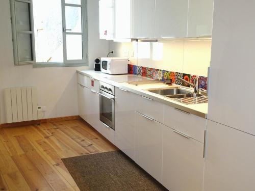 une cuisine blanche avec un évier et un micro-ondes dans l'établissement Agréable maison au centre historique de Foix avec garage, à Foix