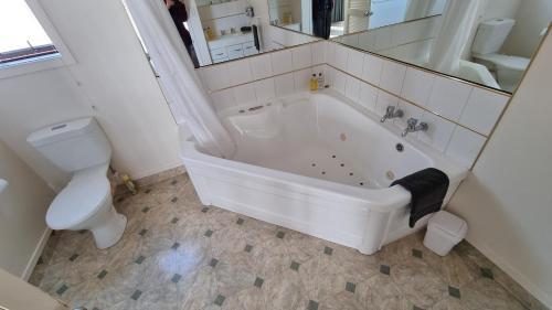 a white bath tub in a bathroom with a toilet at 755 Regal Court Motel in Dunedin
