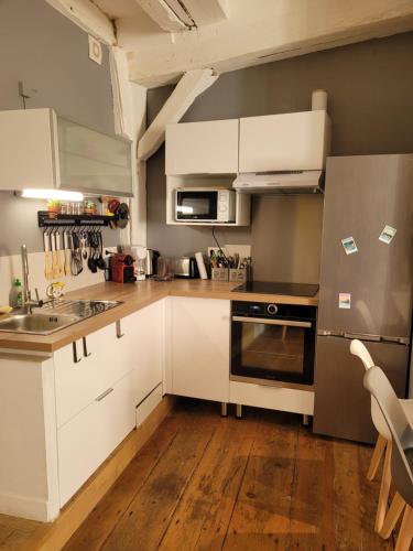 una cocina con armarios blancos y electrodomésticos de acero inoxidable en APPARTEMENT CHIC EN HYPER CENTRE DE VANNES, en Vannes