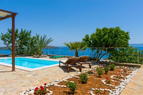 een zwembad met een bankje en bloemen in een tuin bij Elounda Blue Waves in Elounda