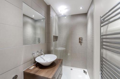 a white bathroom with a sink and a mirror at Roomspace Serviced Apartments - Kinnaird Court in Esher