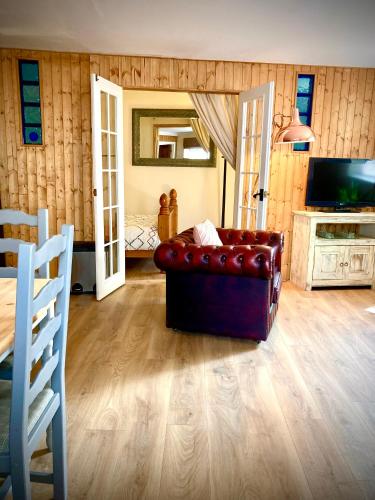 a living room with a leather couch and a television at Aqua Shack at Pure Shores Retreats in Newquay