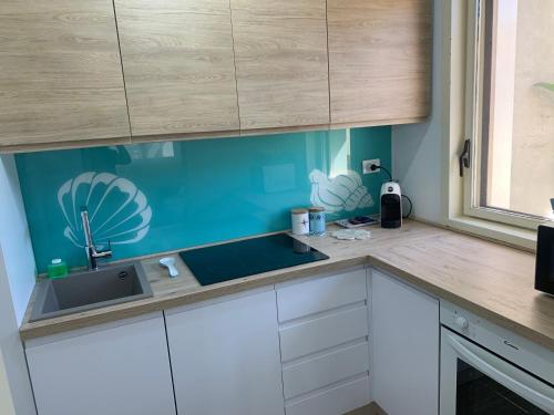 a kitchen with white cabinets and a blue wall at LoVi apartments Porto Palo in Porto Palo