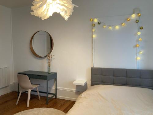 a bedroom with a bed and a table and a mirror at Appartement avec place de parking et box vélos in Montbéliard