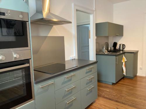 a kitchen with gray cabinets and a stove top oven at Appartement avec place de parking et box vélos in Montbéliard
