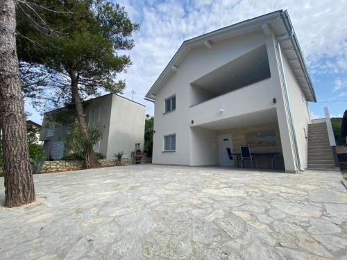 duży biały budynek z drzewem przed nim w obiekcie Dorothy Apartman Vir w mieście Vir