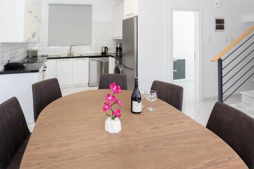 a dining room table with a bottle of wine and flowers at Cosy Paphos Villa - By IMH Travel & Tours in Paphos City