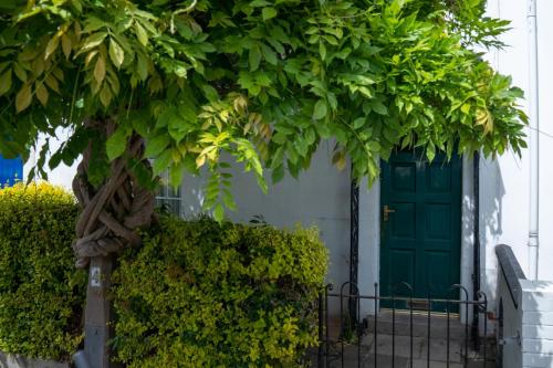 a green door on a white house with a tree at No 33 Stylish and Modern 1 Bed Apartment in Cheltenham