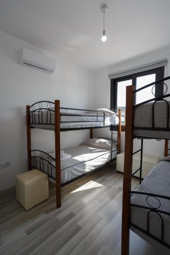 a room with three bunk beds and a window at Cosy Paphos Villa - By IMH Travel & Tours in Paphos City